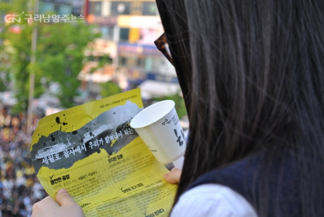 안산문화광장 추모집회에 참석한 학생이 주최 측이 배포한 전단을 읽고 있다.