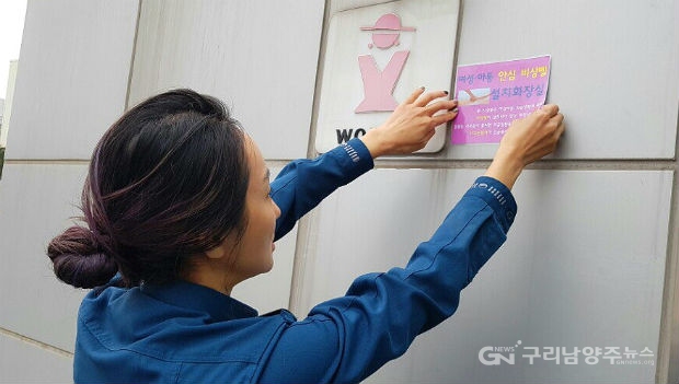 남양주경찰서 경찰관이 비상벨이 설치된 여성화장실 외벽에 비상벨 안내 스티커를 붙이고 있다,.(사진=남양주경찰서)